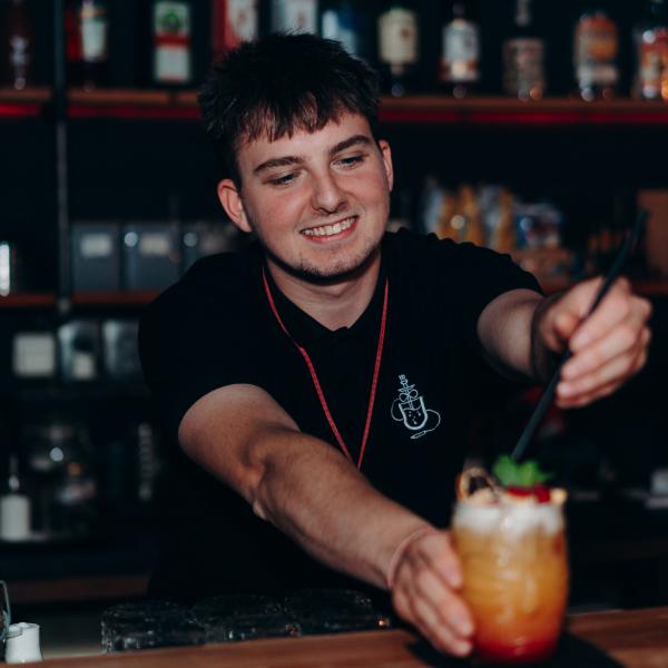 Barman podává drink v baru Uhelna